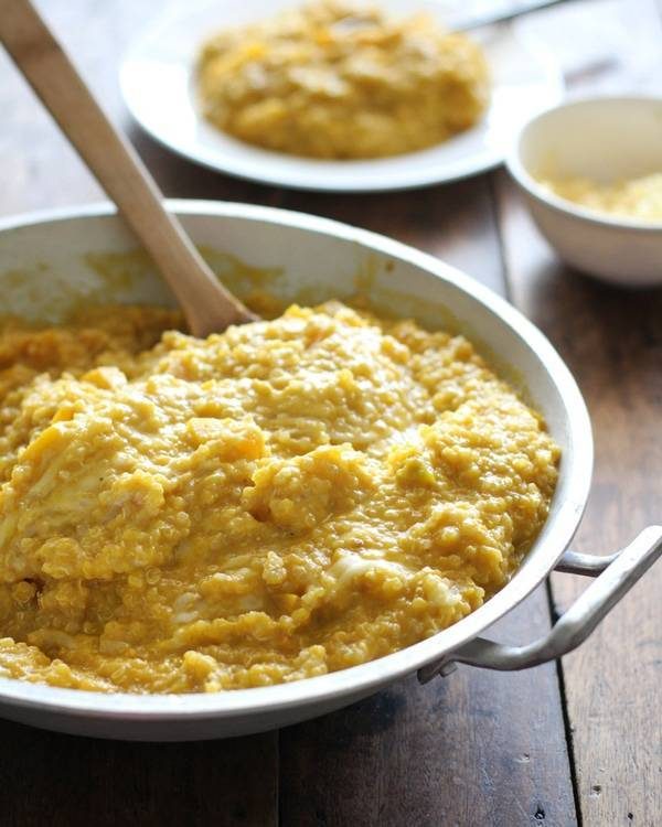 Squash curry quinoa in a skillet with a wooden spoon.