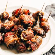 Bacon wrapped dates on a plate with toothpicks in the dates