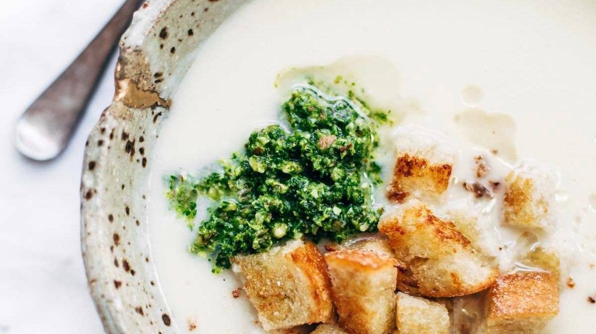 Cheesy Cauliflower Soup in a bowl with pesto and croutons.