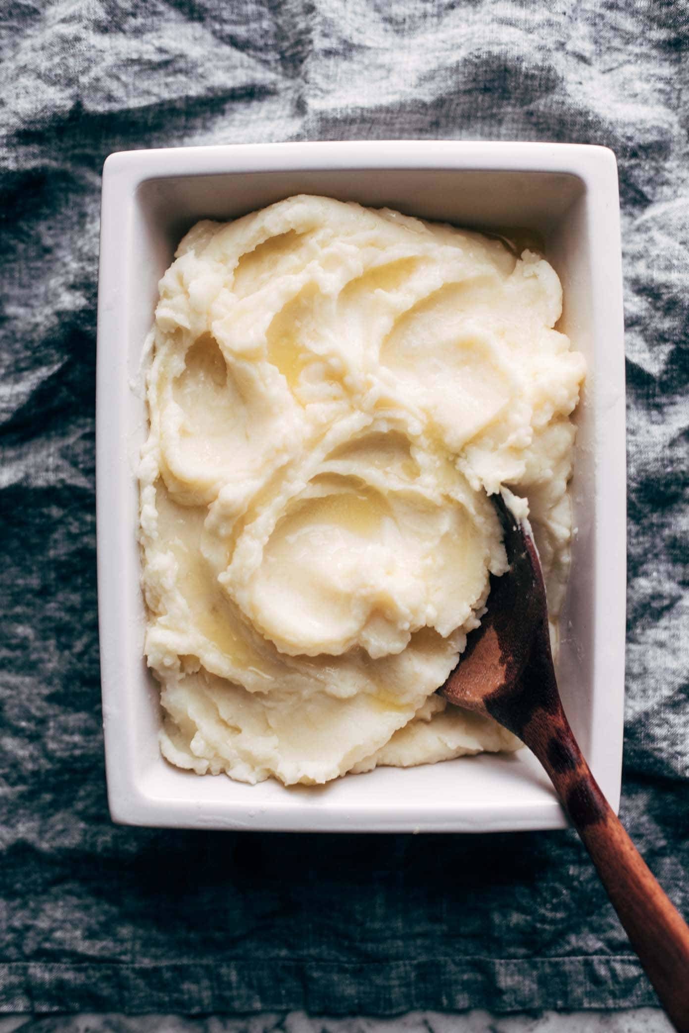 Instant Pot Mashed Potatoes in a white dish with a wooden spoon