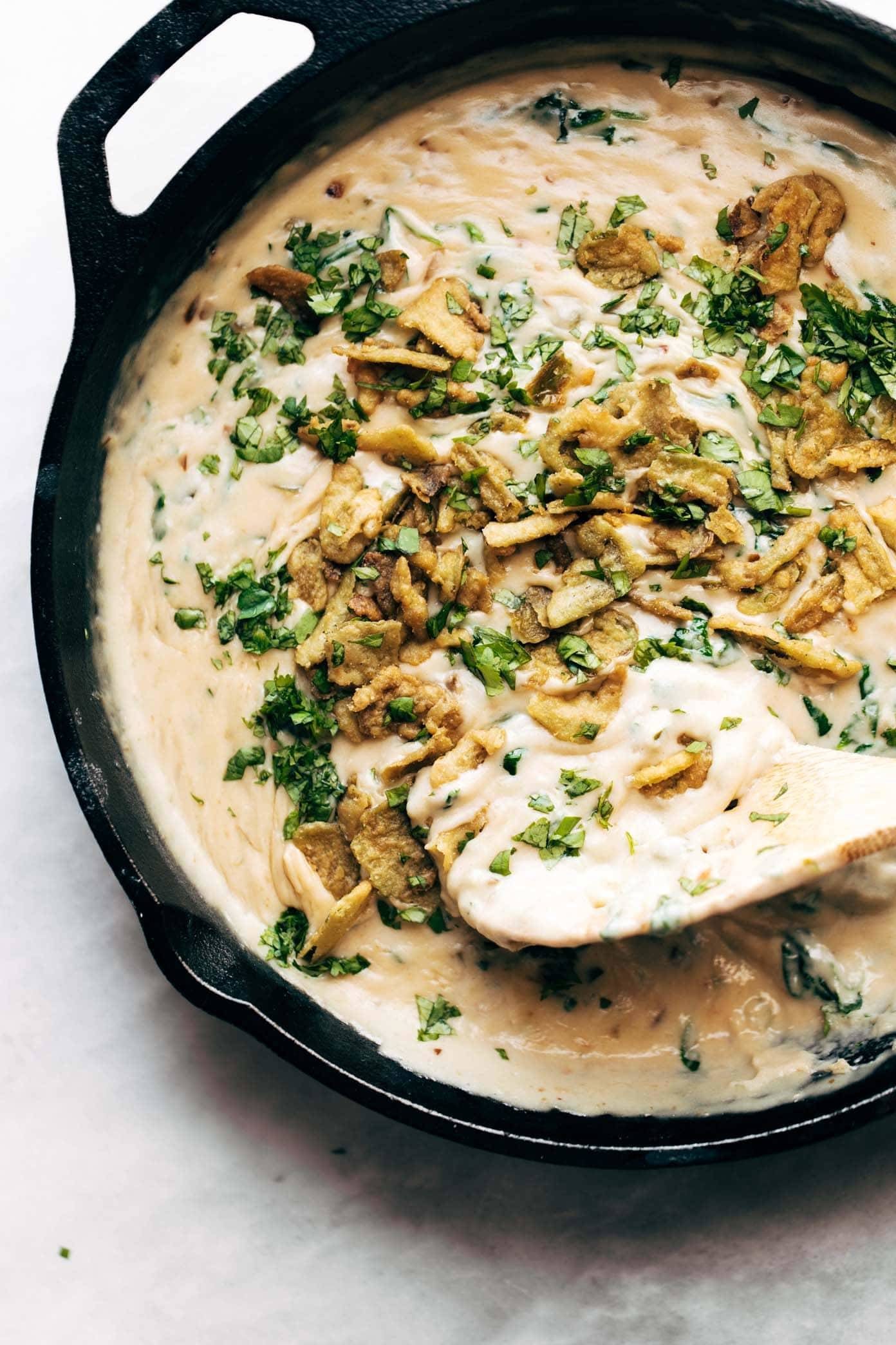 Spinach Queso in a skillet with a wooden spoon