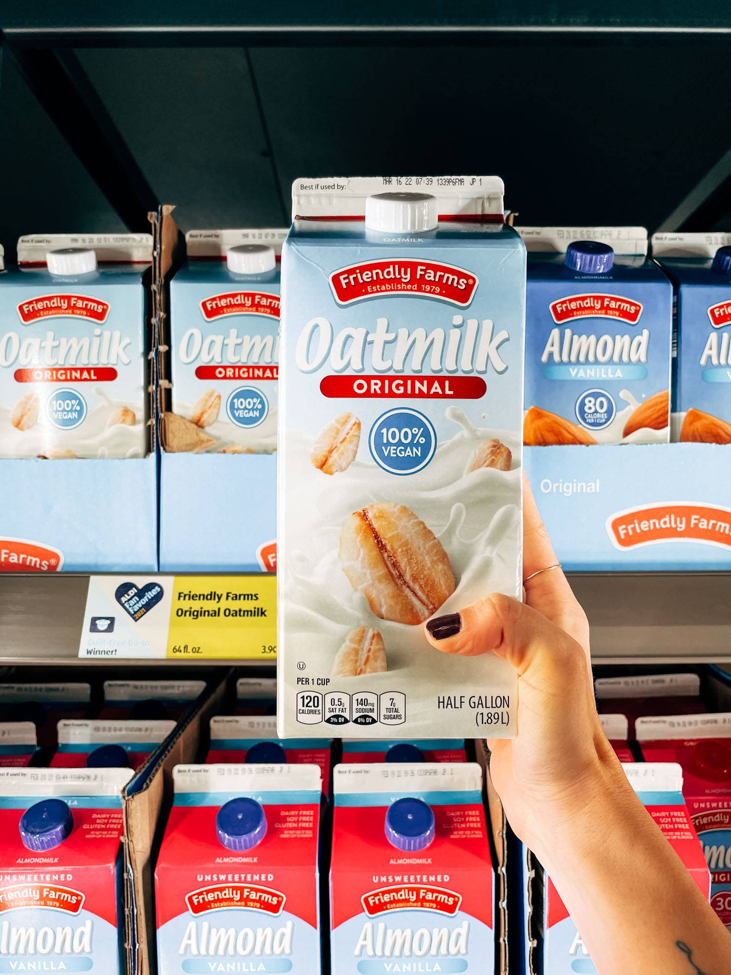 White hand holding a carton of oatmilk