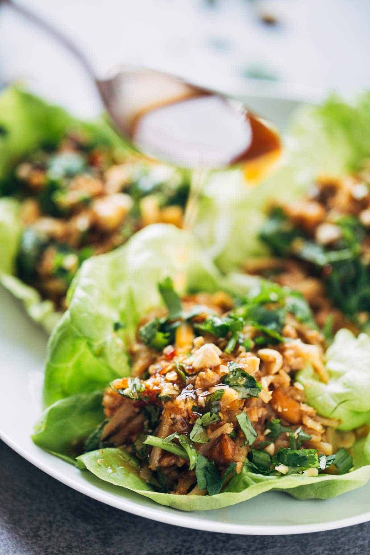Peanut Chicken Lettuce Wraps with a Ginger Garlic sauce on a white plate.