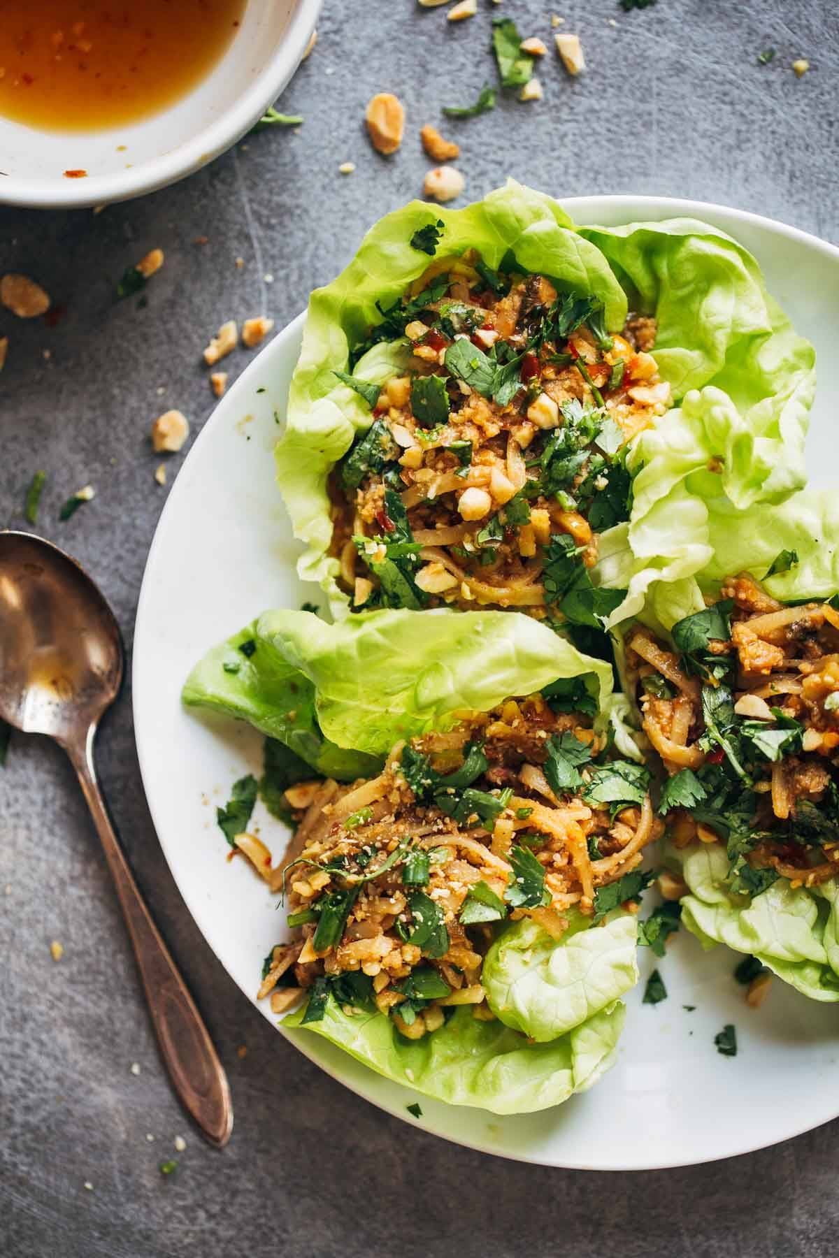 Peanut Chicken Lettuce Wraps with a Ginger Garlic sauce on a white plate with a spoon.
