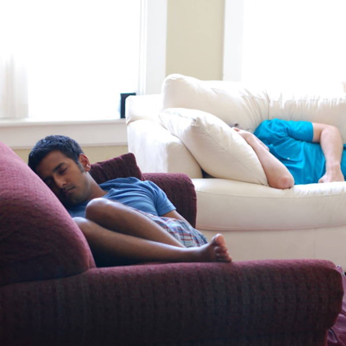 Two men sleeping on couches.