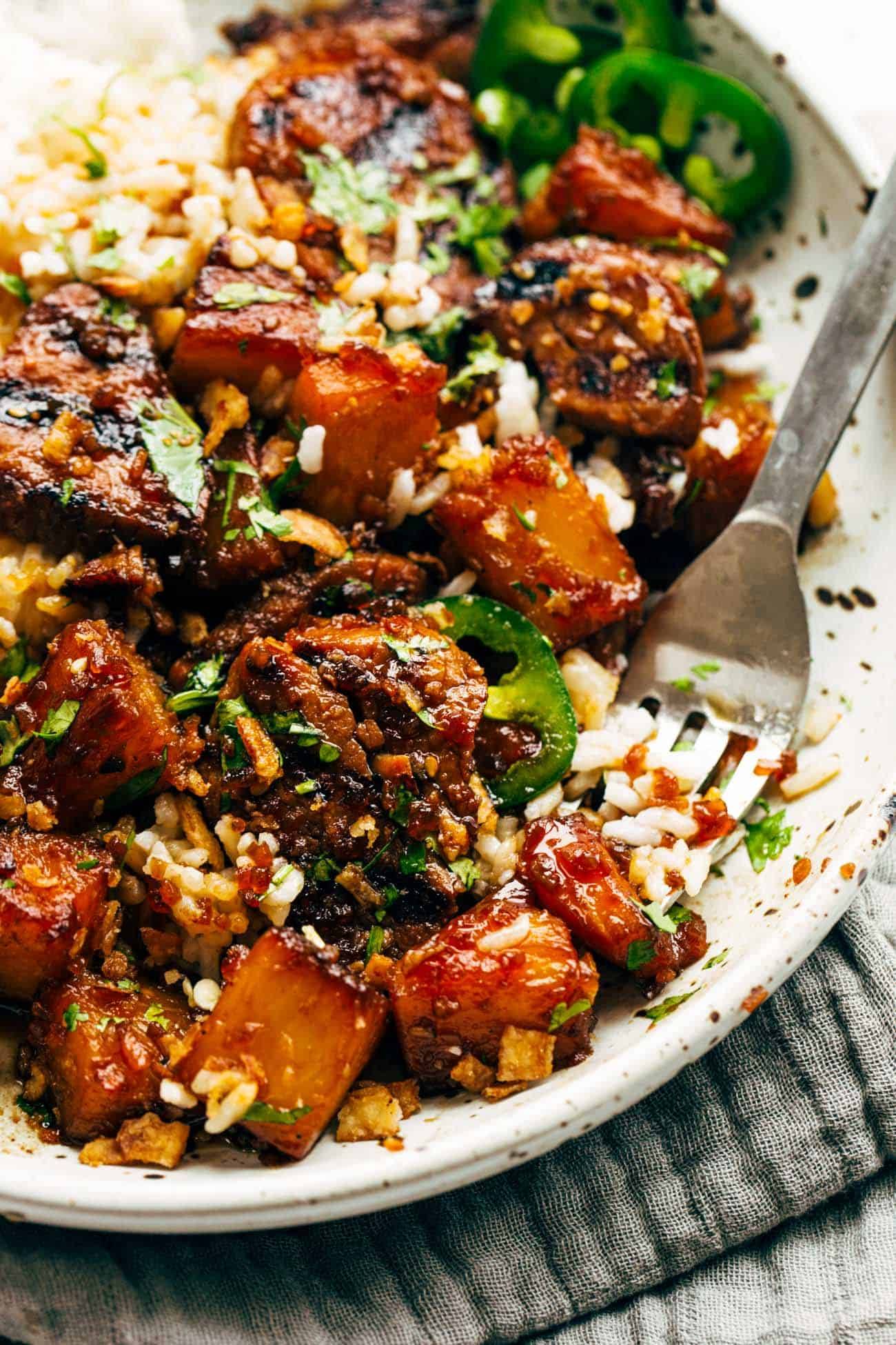 Pineapple pork with coconut rice on a plate with a fork.