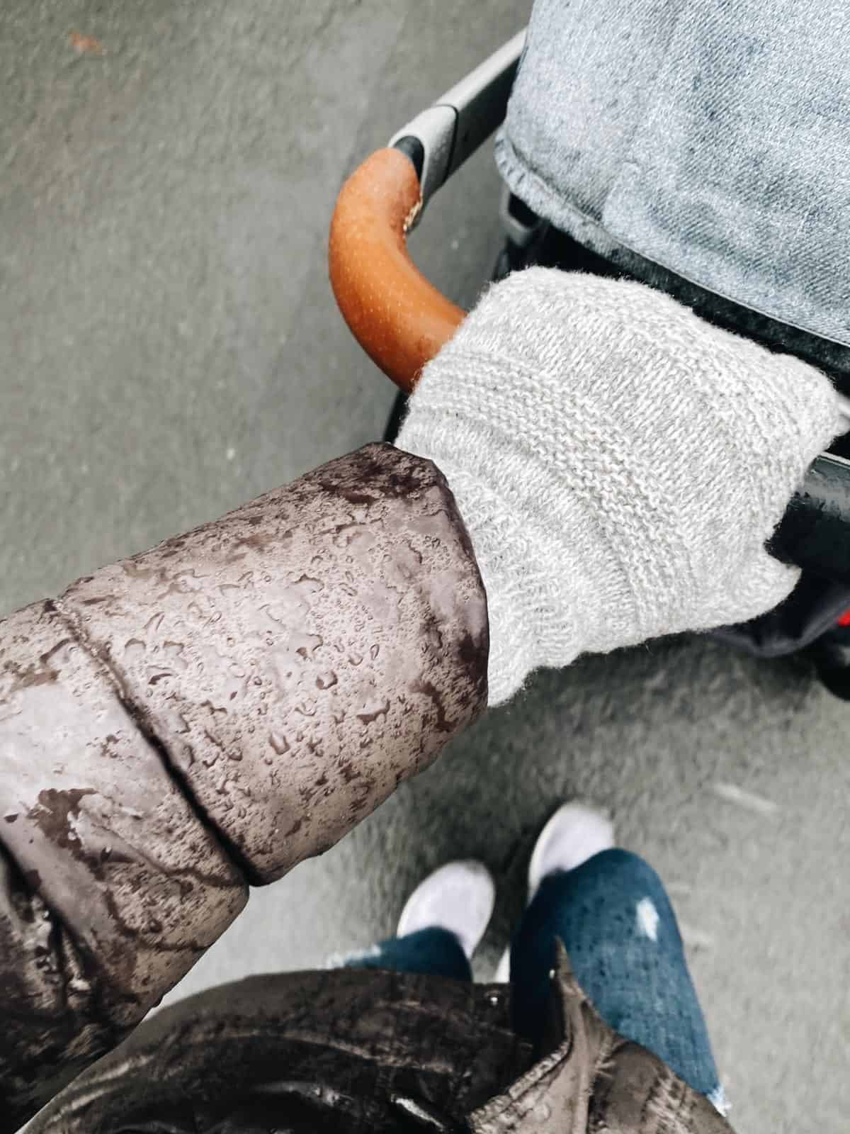 A hand pushing a stroller in the winter.